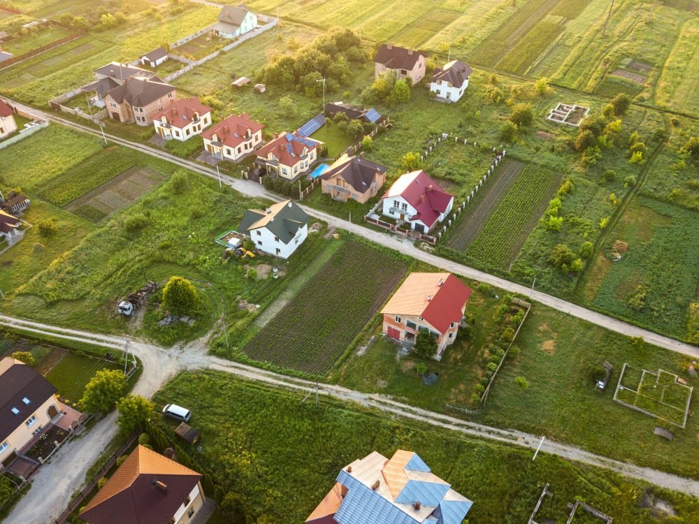 Aerial landscape of small town or village with rows of residential homes and green trees.