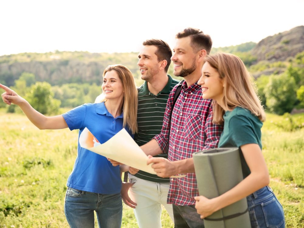 Young people exploring map in wilderness. Camping season